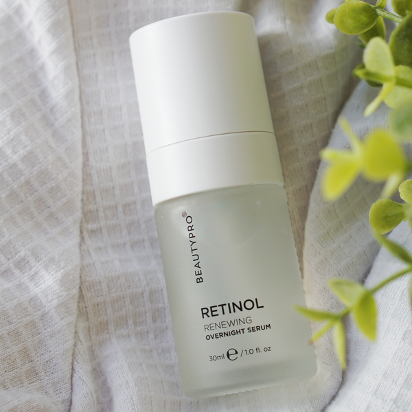 BeautyPro Retinol Renewing Overnight Serum bottle on a light fabric background with a plant.
