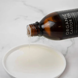 Bottle of Organic Oil being poured into a bowl on a marble surface