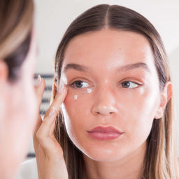 a closeup of a women applying Hello Sunday The One For Your Eyes SPF50to her face