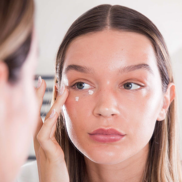 a closeup of a women applying Hello Sunday The One For Your Eyes SPF50to her face