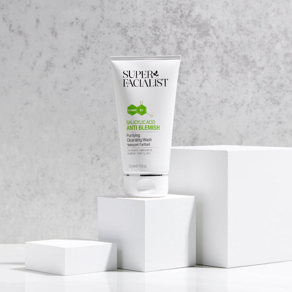 Salicylic acid cleansing wash tube on white cubes against an off white background