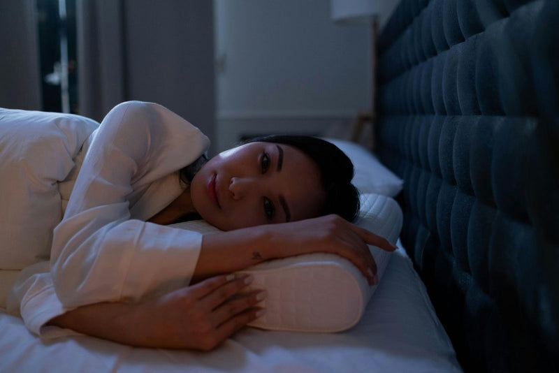 woman with dark hair laid in bed resting her head on the pillow