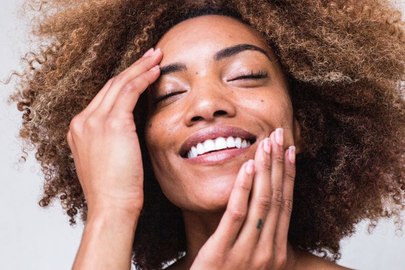 woman with her hands to her face smiling