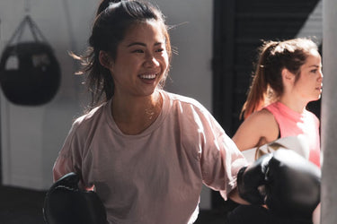 Woman at a boxing session wearing black boxing gloves