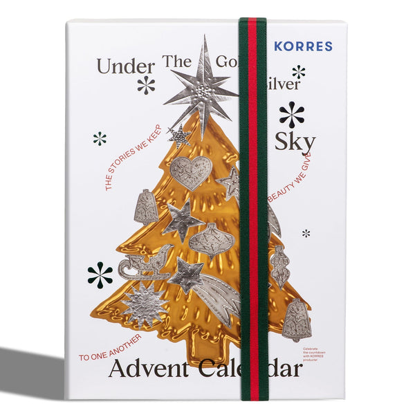 A Korres Advent Calendar with a white cover, featuring a gold and silver Christmas tree illustration, a green and red elastic closure band, and the text 'Under The Gold and Silver Sky' and 'Advent Calendar'.