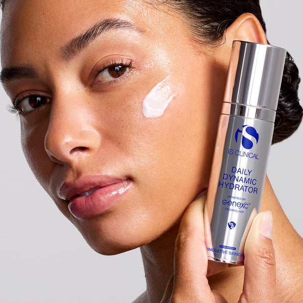 Woman applying skincare product to her face with a bottle labeled 'Daily Dynamic Hydrator' in the foreground.