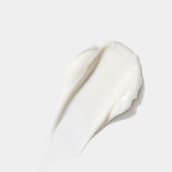 A thick, creamy white product smear, likely a skincare cream or serum, swirled on a clean, light gray background.