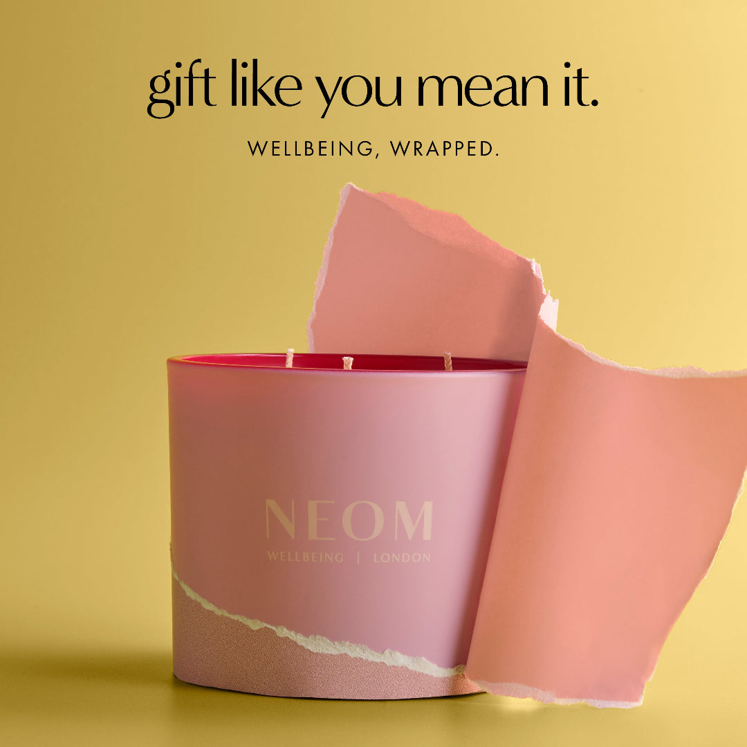Neom candle with pink packaging on a yellow background