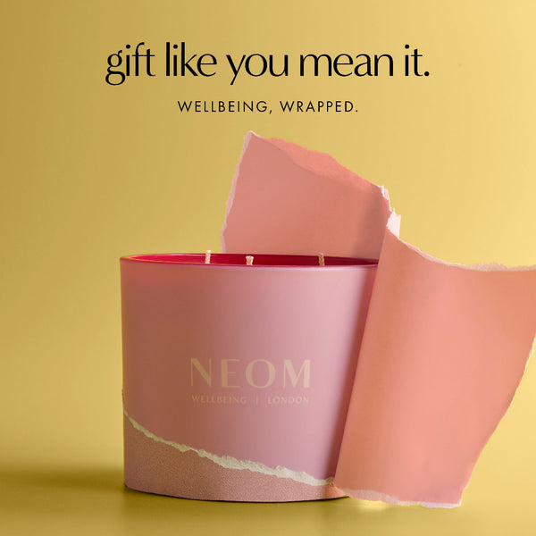 Neom candle with pink packaging on a yellow background
