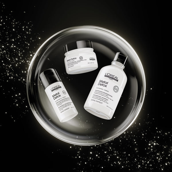 Three L'Oréal Paris Metal Detox skincare products arranged inside a glowing circular metallic tray on a black background with sparkling light effects.
