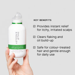 A hand holds a white bottle of Philip Kinsley Flaky Itchy Scalp shampoo against a light gray background, with key benefits listed in black text on the right.