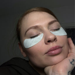 Woman with under-eye patches on a dark background