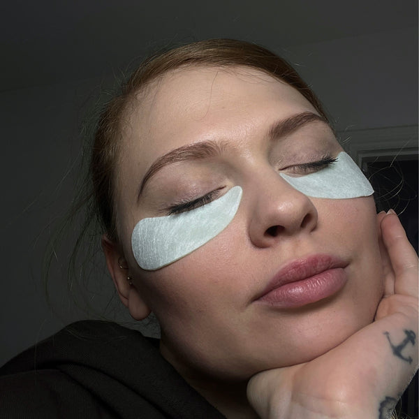 Woman with under-eye patches on a dark background