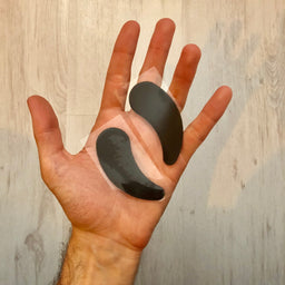 Two black foot pads on a person's palm against a wooden background