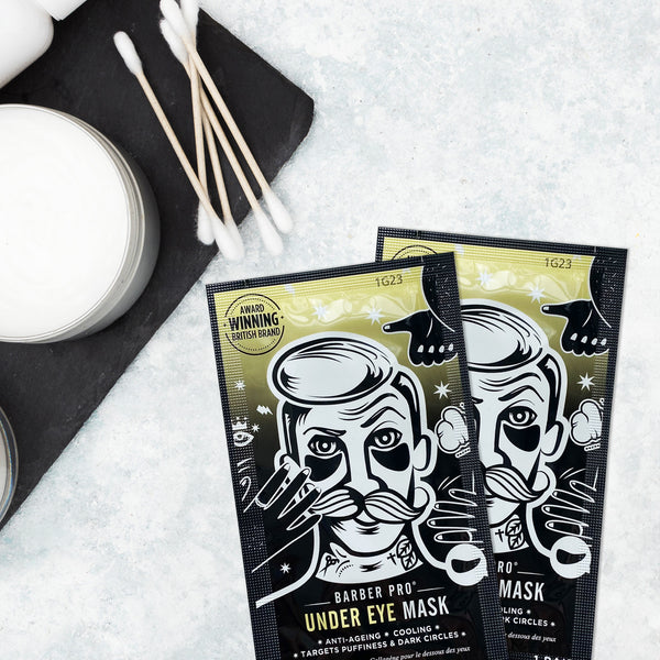 Two Barber Pro under eye mask packages on a textured surface with cotton swabs and a container.