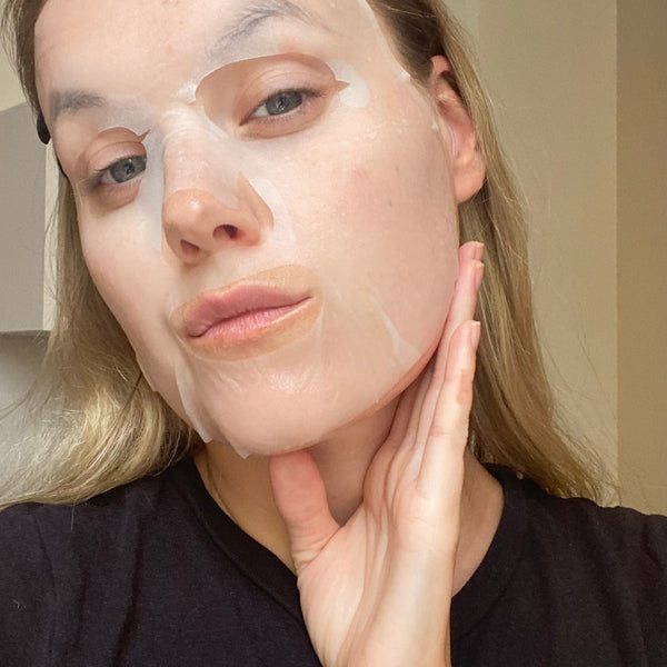 Woman applying a face mask with a neutral background