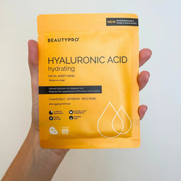 Hand holding a BeautyPro hyaluronic acid facial sheet mask package against a light background