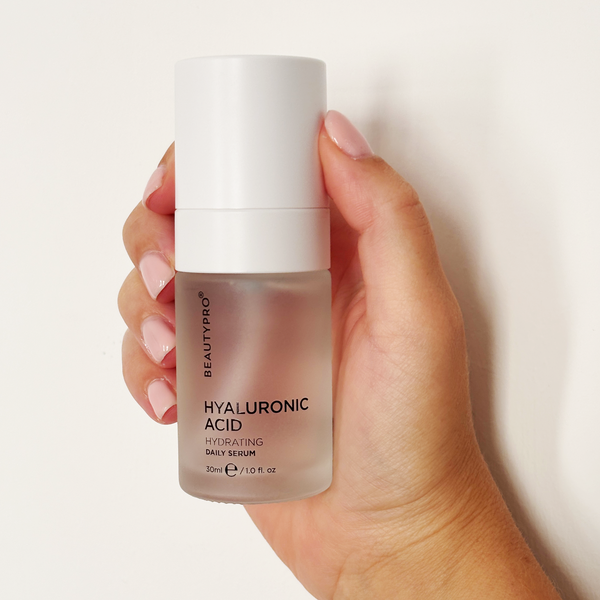 Hand holding a bottle of BeautyPro Hyaluronic Acid serum against a white background