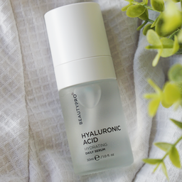 BeautyPro Hyaluronic Acid serum bottle on a textured fabric background with greenery.