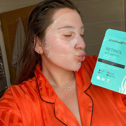 Woman applying a facial mask with a product package labeled 'Retinol' in the background.