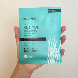 Hand holding a Beautypro Retinol anti-ageing facial sheet mask packaging against a plain background