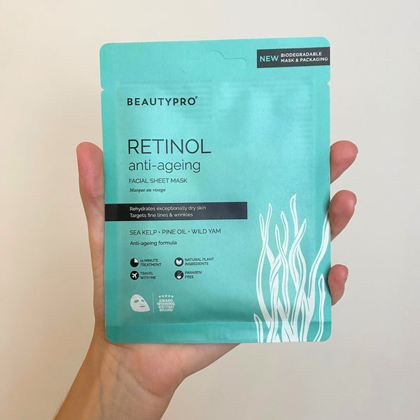 Hand holding a Beautypro Retinol anti-ageing facial sheet mask packaging against a plain background