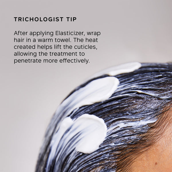 Close-up of a person's dark hair with white cream applied, with text reading 'TRICHOLOGIST TIP' and instructions about wrapping hair in a warm towel after applying Elasticizer.