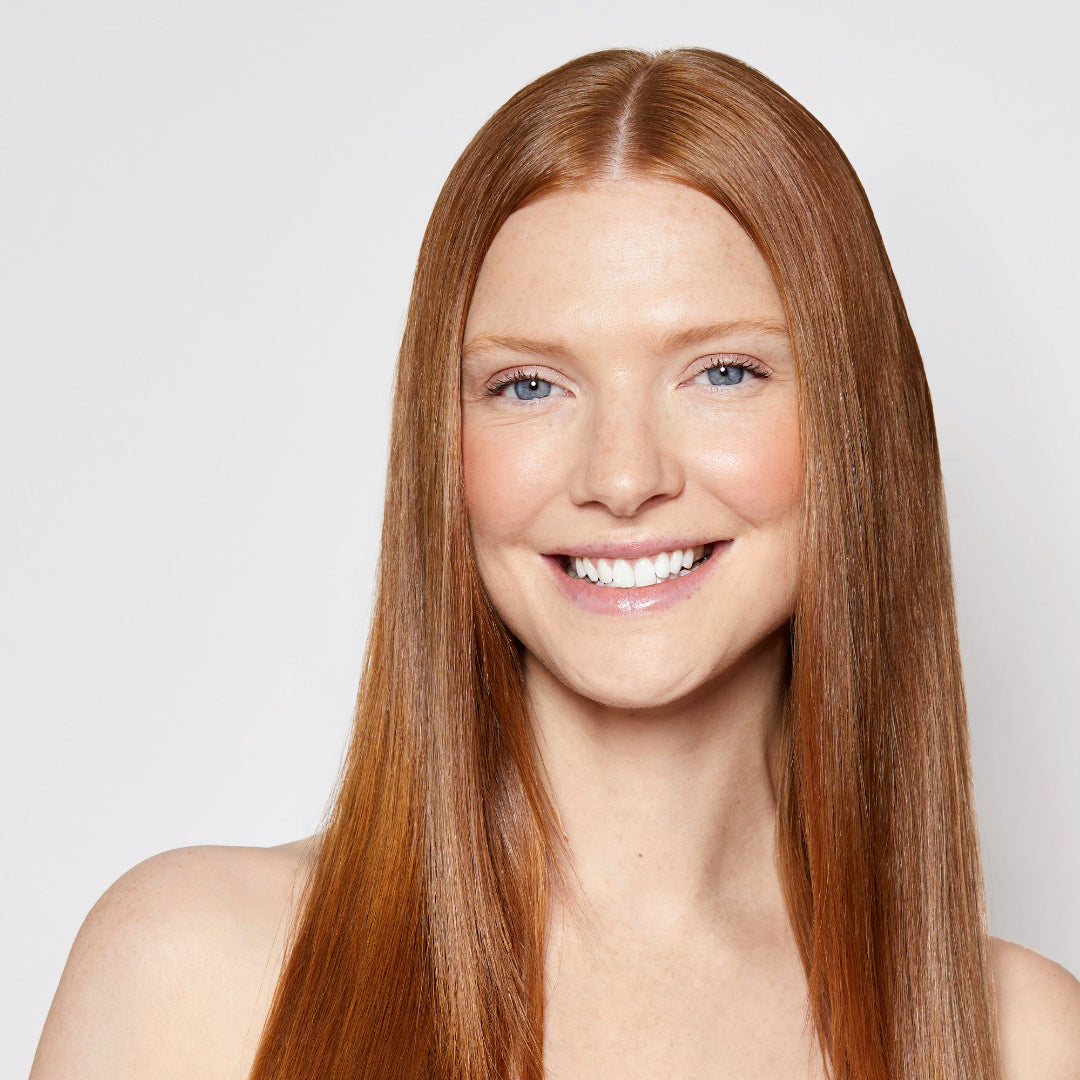 Woman with long straight red hair on a plain background