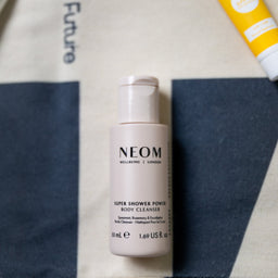 Neom body cleanser bottle with other products on a patterned background
