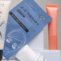 Skincare products including eye therapy mask, cream, and serum on a gray background