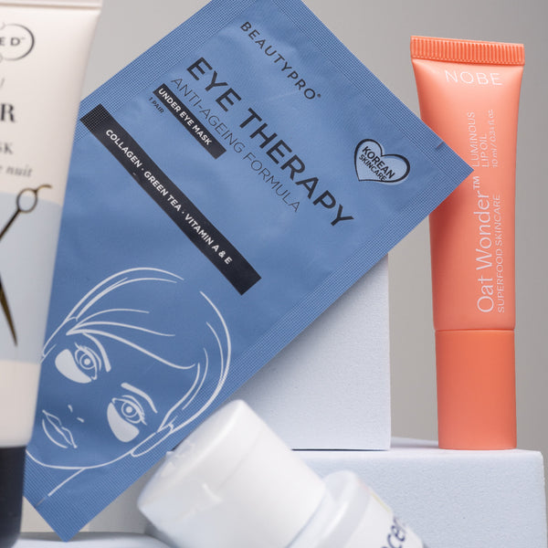 Skincare products including eye therapy mask, cream, and serum on a gray background