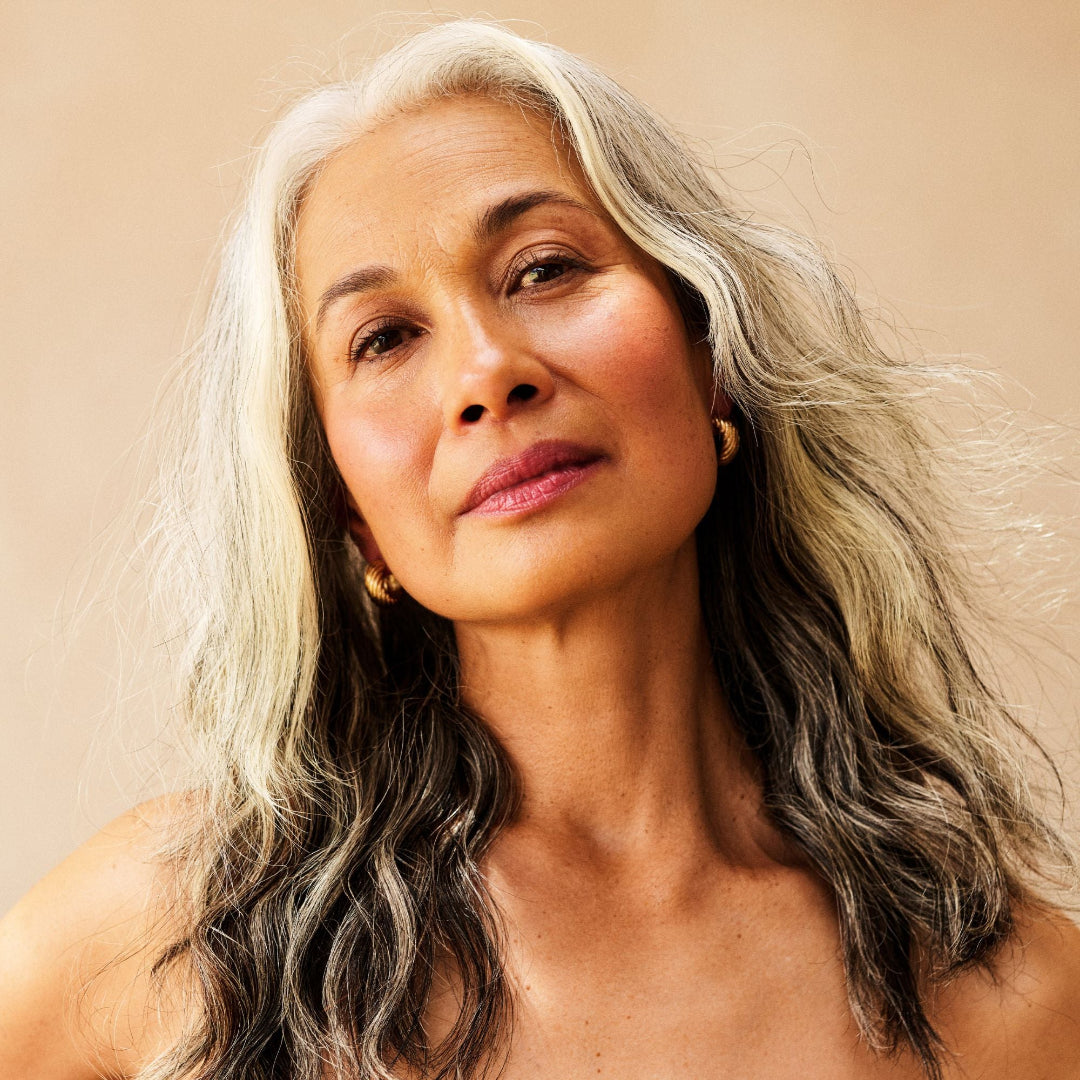Woman with gray hair against a beige background