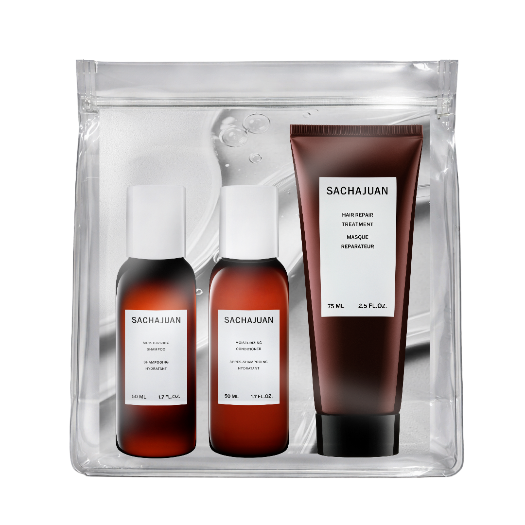 Sachajuan hair care set in a clear zippered pouch, featuring a brown hair retainer treatment tube and two brown bottles with white caps, shown on a white background.