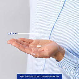 A person in a light blue and white striped shirt holds an open hand showing a single white capsule pill, with text indicating its size is 0.629 in.