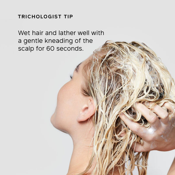 A woman with wet blonde hair lathering shampoo, shown in profile against a light gray background with the text 'TRICHOLOGIST TIP' and a short instructional tip about wetting and kneading the scalp for 60 seconds.