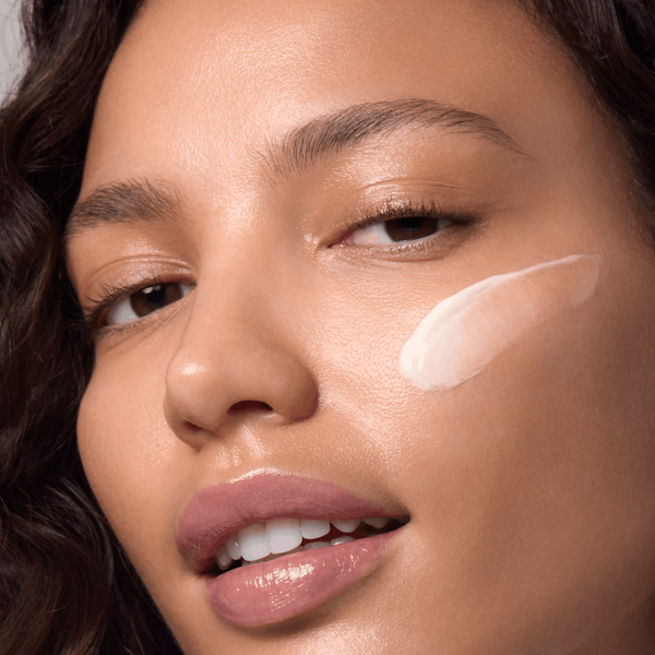 Close-up of a woman's face with a cosmetic product applied to her cheek.