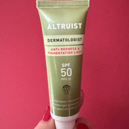 Tube of Altruist Dermatologist SPF 50 sunscreen held against a red background