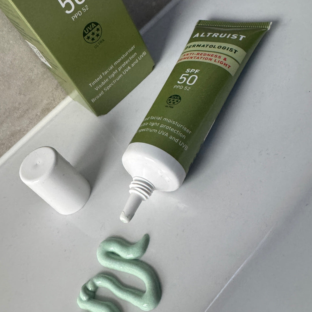 Green skincare product with applicator on a white surface