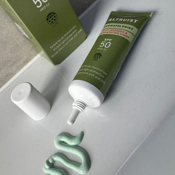 Green skincare product with applicator on a white surface
