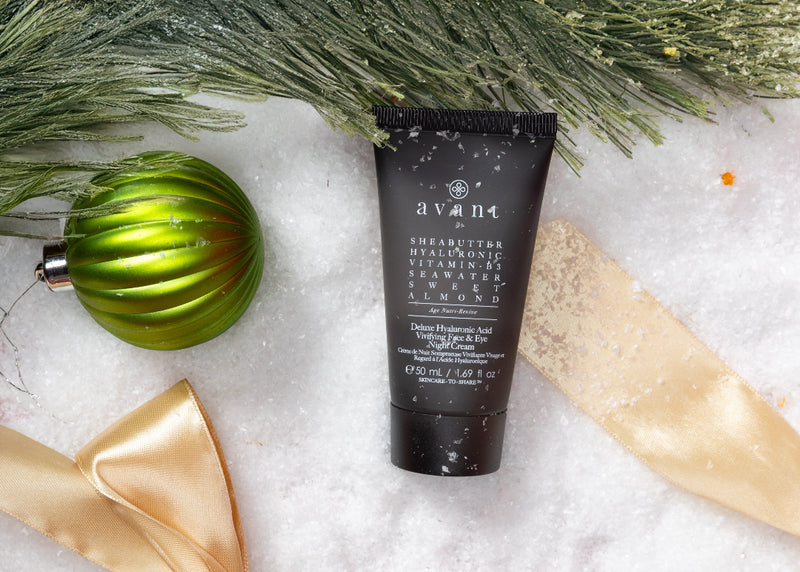 Tube of Avrimi skincare product on a snowy surface with greenery and a gold bow.