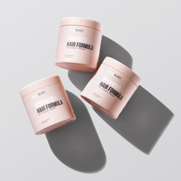 Three containers of BURST Advanced Hair Formula on a light gray background