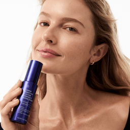 Woman holding a blue skincare bottle against a white background