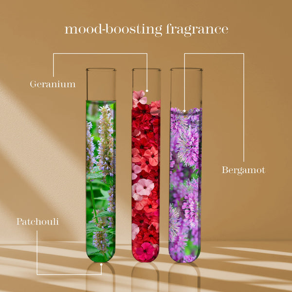 Three labeled glass test tubes filled with floral imagery on a warm beige background, with text reading 'mood-boosting fragrance' and labels 'Geranium,' 'Bergamot,' and 'Patchouli.'.