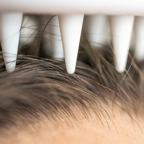 Close-up of a hairbrush with bristles against skin