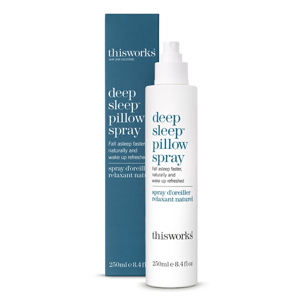A bottle of thisworks Deep Sleep Pillow Spray next to its blue and white packaging box, set against a plain white background.