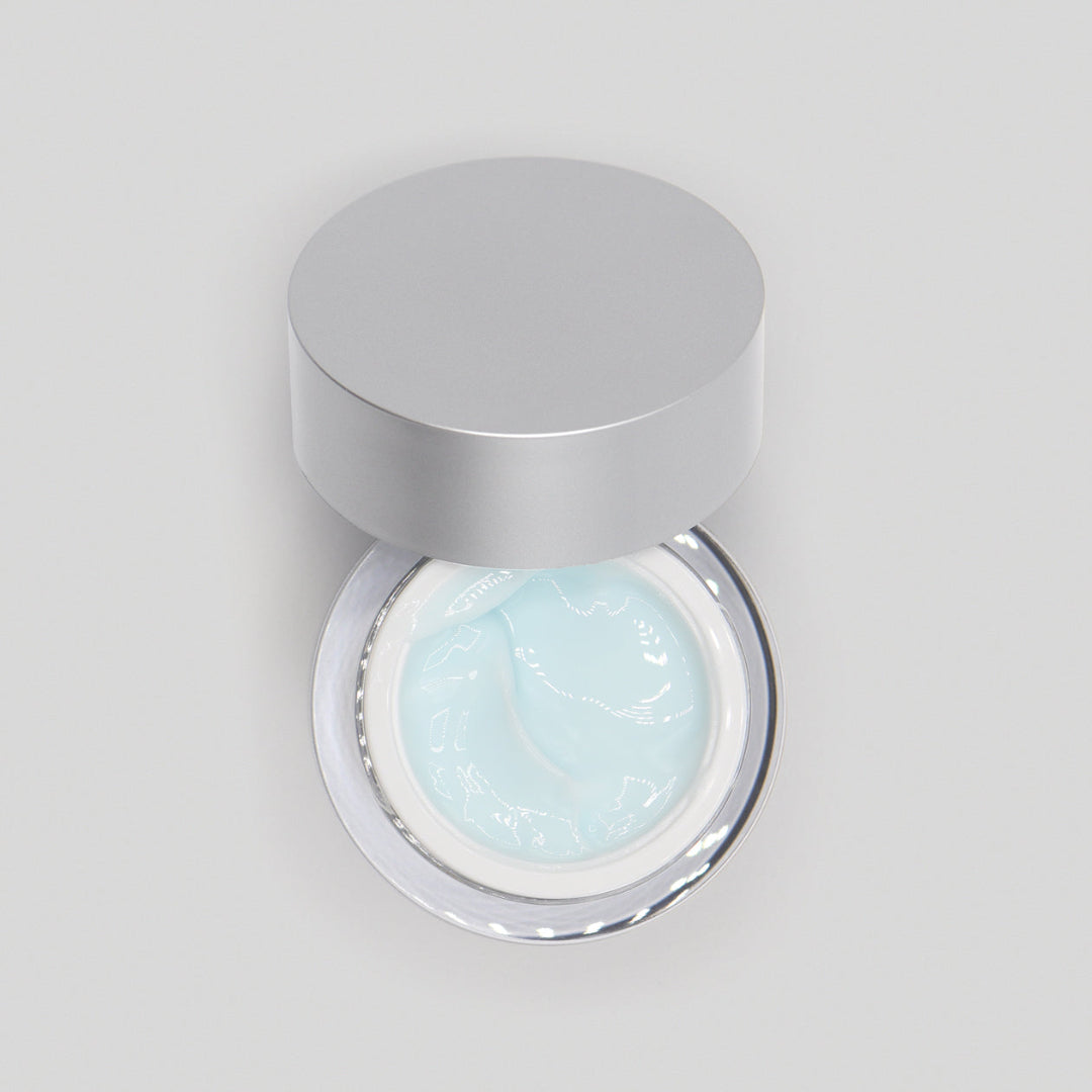 Jar of light blue cream with a silver lid on a gray background