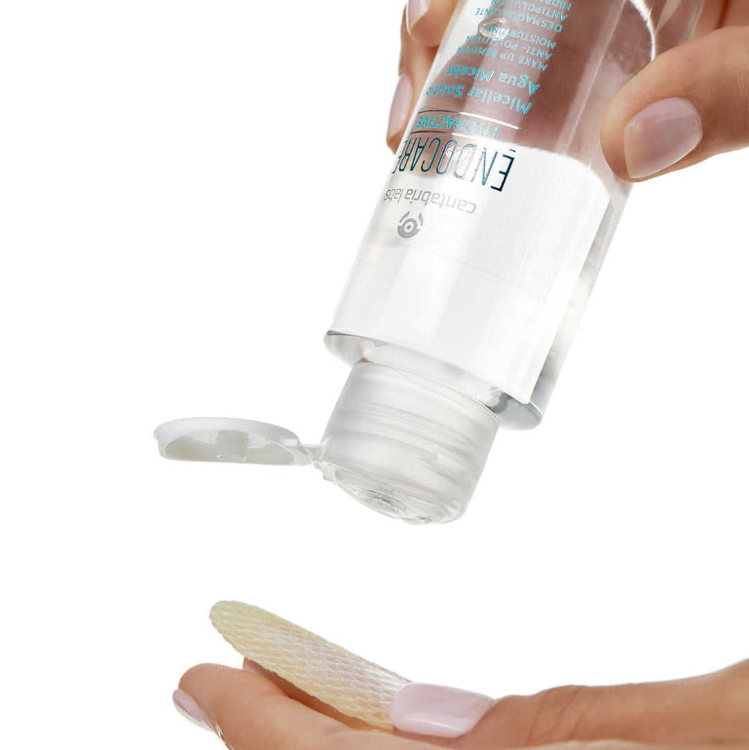 Hand holding a cosmetic bottle with a small amount of product on a white background
