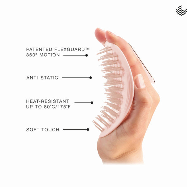 A hand holds a light pink oval hairbrush with soft bristles against a white background, with text callouts reading 'PATENTED FLEXGUARD 360° MOTION,' 'ANTI-STATIC,' 'HEAT-RESISTANT UP TO 80°C/175°F,' and 'SOFT-TOUCH.'.