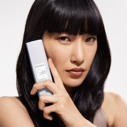 Woman holding a KERASTA product against a white background