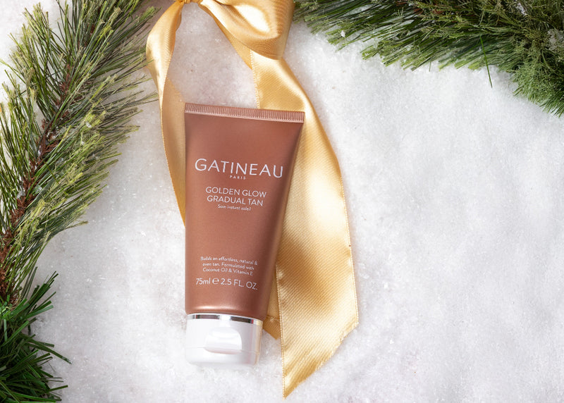 Gatineau Golden Glow Gradual Tan tube with gold ribbon on a snowy background